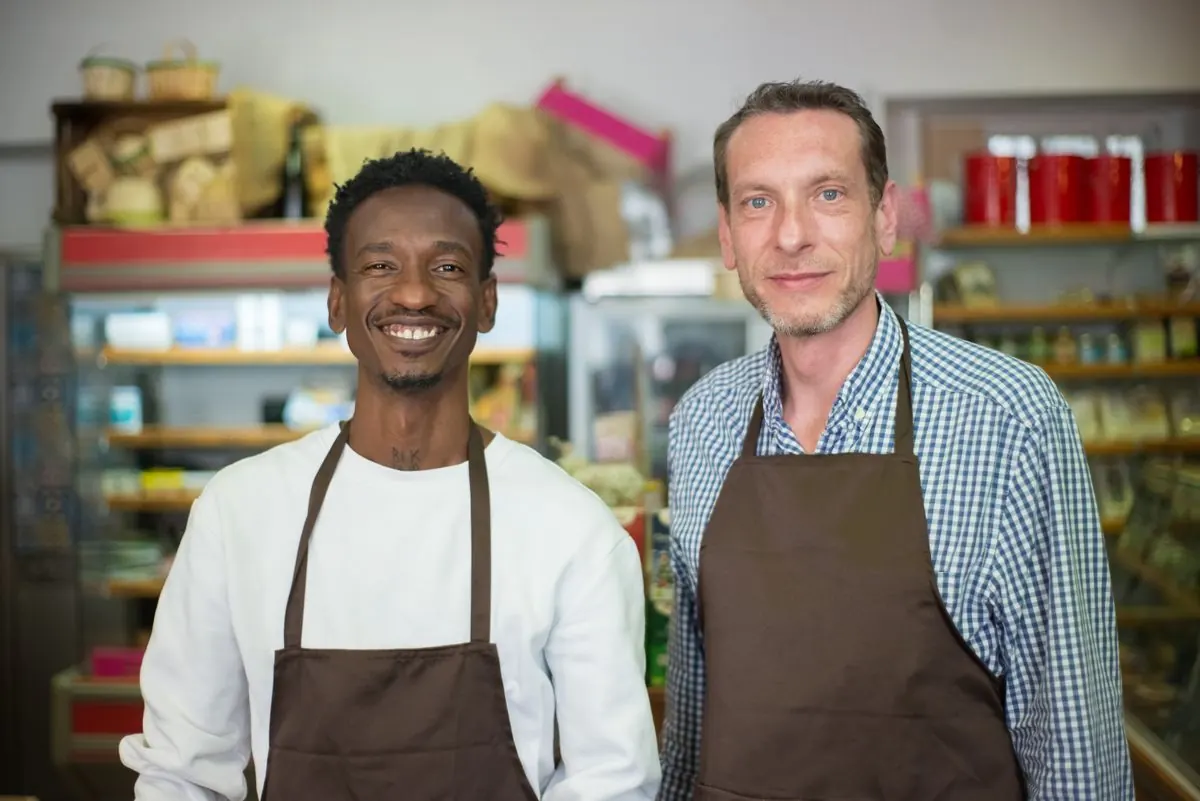 Two small business owners smiling in the doorway of their shop